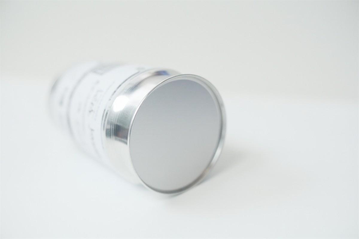 The plain silver back panel of an aluminum beverage can laid on its side on a white counter.